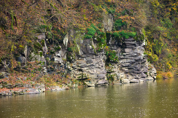 rocky cliff over the river in forest. beautiful autumn background with lots of textures