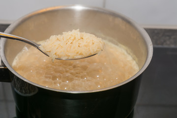 Reis auf dem Löffel - Kochender Reis in der Pfanne 