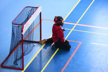 Unidentifiable floorball goalkeeper during mach. Child boy player scoring during the floorball match. Children playing floorball