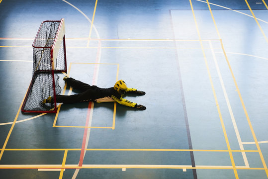 Unidentifiable floorball goalkeeper during mach. Child boy player scoring during the floorball match. Children playing floorball
