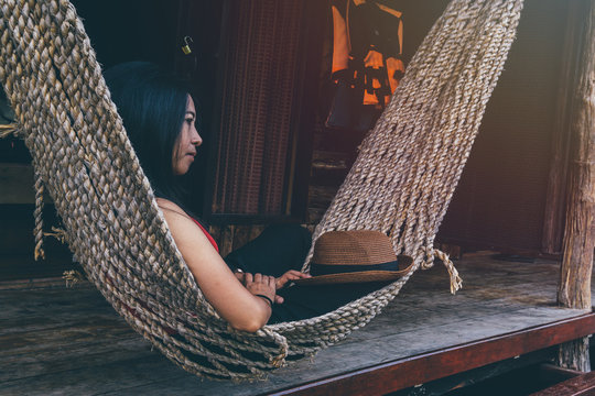Asian girl on wood cradle in the resort., kanchanaburi thailand., Asian woman is sleeping on the cradle., relaxing concept. image vintage style.
