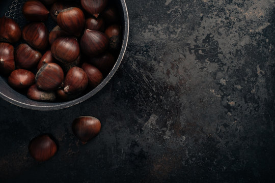 Chestnuts on dark black rustic background. Top view, copy space.