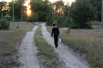 The boy is carrying the jar of fresh cow mik in Ukrainian village