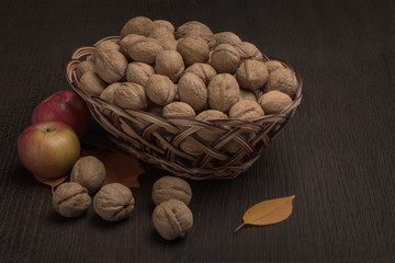 Ripe walnuts in a basket on a wooden background
