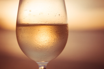 Wineglass of white wine at sunset dramatic sky background. Closeup. Travel vacations concept.