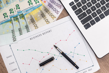 business graph with pen and laptop, euro banknote on desk