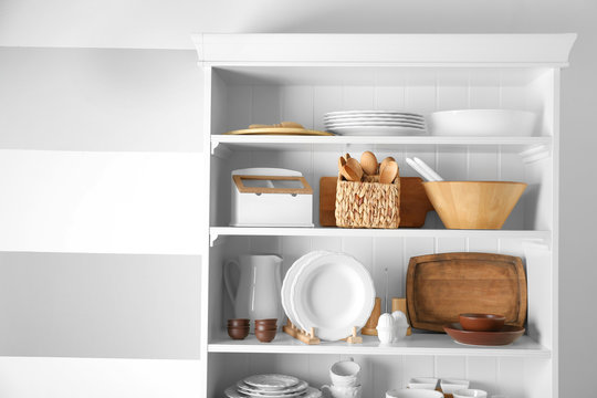 Storage stand with tableware and kitchen utensils indoors