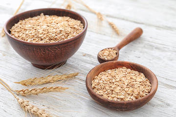 Bowl and plate with raw oatmeal on table
