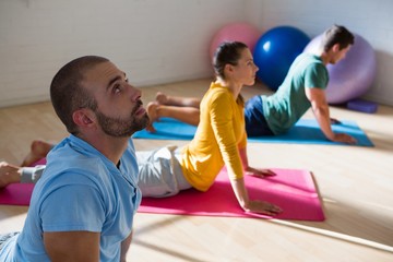 Instructor with students practicing cobra pose in studio