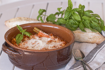 A terracotta pot with tripe with beans and grated parmigiano cheese.
