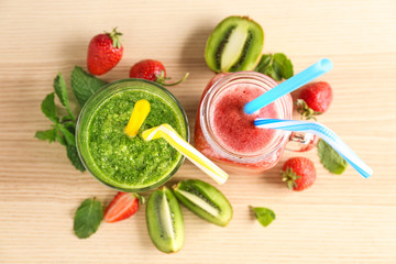 Glassware with delicious kiwi and strawberry smoothies on light background