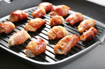 Grill pan with bacon wrapped chicken, closeup