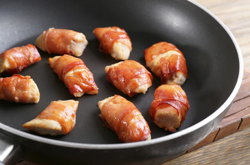 Bacon wrapped chicken in frying pan, closeup