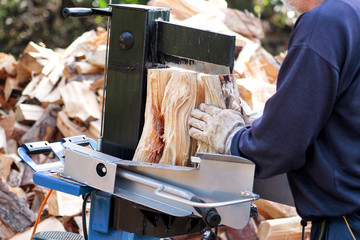 Saw cutting wood for winter. A man cutting firewood for the winter using a modern machine lumber saw. Wood industry. Heating season, winter season. Renewable resource of energy. Environmental concept.