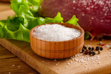 salt-cellar on a cutting board next to meat and salad