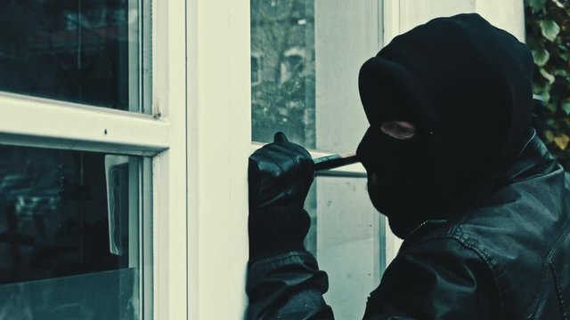 intruder or burglar with crowbar break door to enter the house