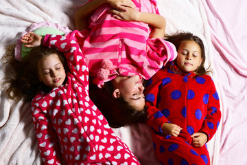 Girl friends in pajamas sleep in bed, top view