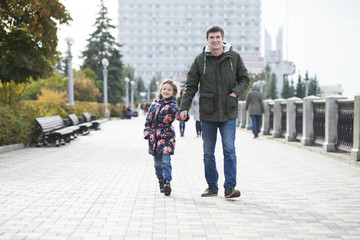 Young father walks with his daughter in an autumn park