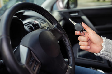 Happy customer just bought a car at car dealership. He sit ia new car and show a key