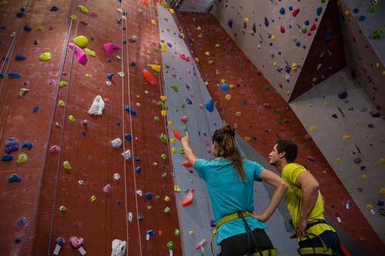 Athletes interacting while standing by climbing wall in gym