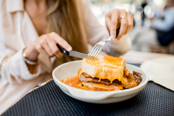 Eating traditional portuguese meat sandwich with tomato sauce called francesinha at the restaurant in Porto city - obrazy, fototapety, plakaty