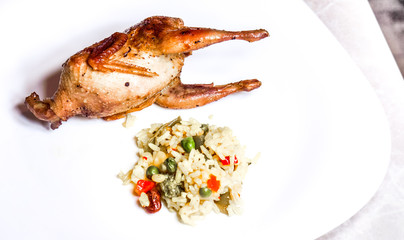 fried quail with fresh vegetables on the wooden board on green grass.