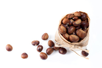 edible chestnuts - a bag of fresh, raw chestnuts sprinkled on a white background