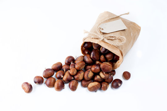 edible chestnuts - a bag of fresh, raw chestnuts sprinkled on a white background