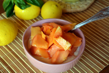 Healthy breakfast ripe chopped papaya with cottage cheese on a bowl on a wooden table.