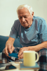 Senior Man Sitting On Bed At Home Taking Medication