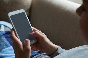 Woman using mobile phone on sofa in living room