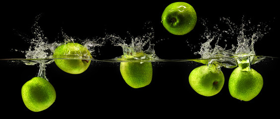 Fototapeta na wymiar Green apple falling in water on black background