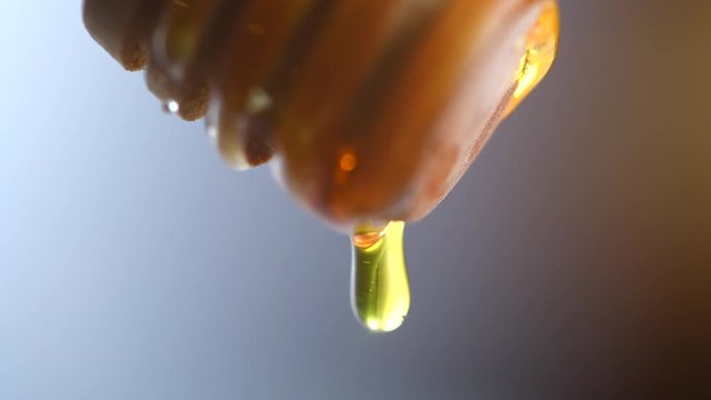 Healthy organic thick honey dripping from the wooden honey dipper. 4K UHD video footage 3840X2160