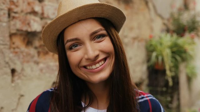 Portrait of brown-haired young charming woman with gray blue eyes. Woman looking at camera and smiling. Outdoor. Close-up