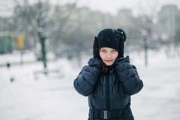 girl covered her mouth with gloves. girl made a gesture, silence. child walks after school on street in a snowfall.