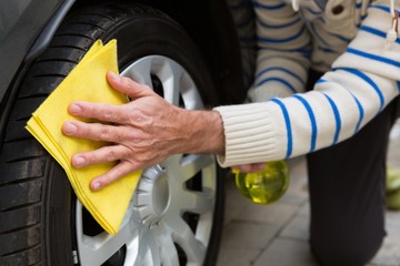 Auto service staff cleaning a tyre with duster
