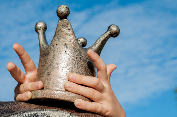 The golden crown in the hands of the child