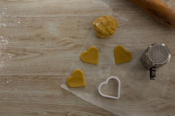 Raw cookie dough with heart shaped cookie cutter and flour
