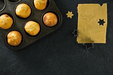 Plain cupcakes in baking tray with star shape dough and cutter