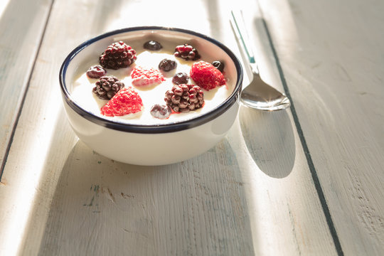 Healthy homemade  yoghurt  with fresh blueberries, raspberries and blackberries  with early summer morning light, shallow depth of field