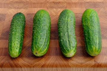 fresh green cucumbers on wooden cutting board close-up