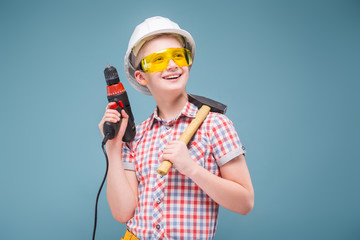 blonde teenager blonde in the construction helmet with a screwdriver and hammer