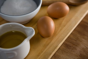 Brown eggs and sugar on chopping board