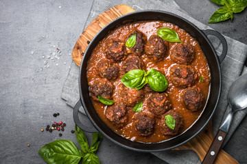 Meatballs in tomato sauce on a black background.