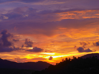 Twilight beautiful evening cloudy sky  after sunset background . There are silhouette mountains and trees.