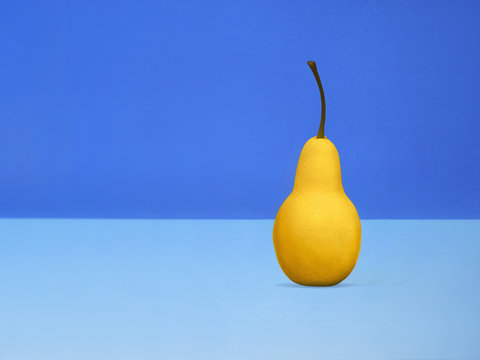 Pear Pop art One yellow pear is standing upright on blue background Trendy still life with fruit