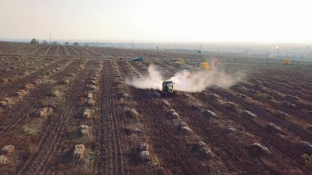 Aerial tractor sprinkles chemical fertilizers on the field of walnut and hazelnut farm frontal view
