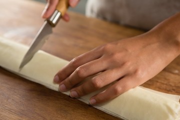 Fototapeta na wymiar Woman slicing dough on chopping board