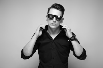 Handsome young businessman in costly watch, sunglasses and black shirt