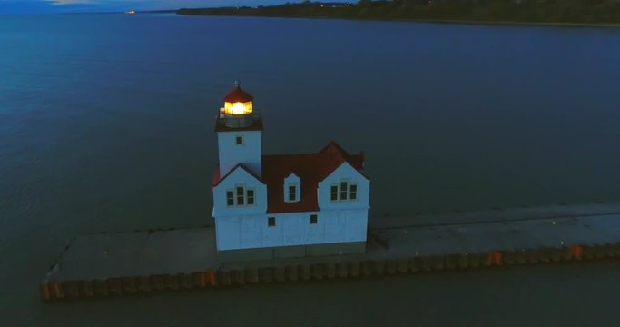 Lake Michigan Lighthouse shines a bright beacon into the vast twilight, aerial fly around. Lighthouses are symbolic of safety, welcome and hope.